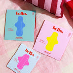 Hello Period liner and pad packaging styled on a bed