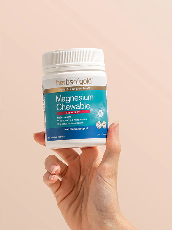 Hand holding the Herbs of Gold Magnesium Chewable tub