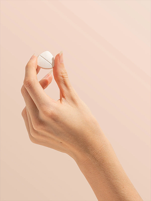Hand holding a Herbs of Gold Magnesium Chewable raspberry tablet
