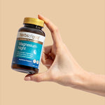 Hand holding the Herbs of Gold Magnesium Night bottle