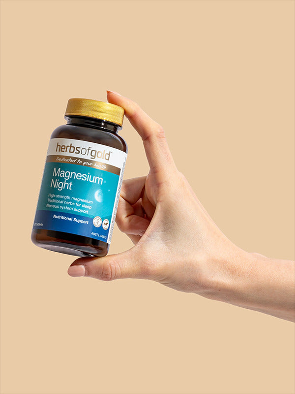 Hand holding the Herbs of Gold Magnesium Night bottle