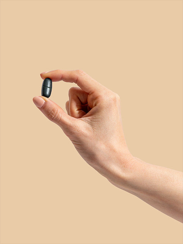 Hand holding a Herbs of Gold Magnesium Night tablet