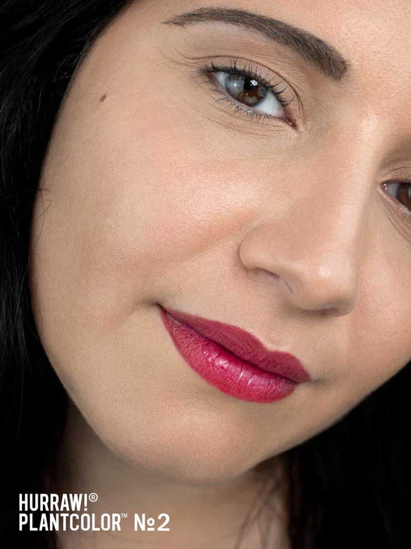 Close-up of a model wearing the bright pink shade from Hurraw! Rouge à Lèvres Plantcolour No 2, with the shade label visible.