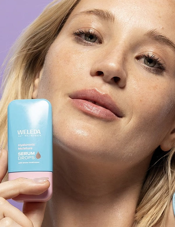 Model holding Weleda Hyaluronic Moisture Serum Booster Drops beside hydrated glowing skin