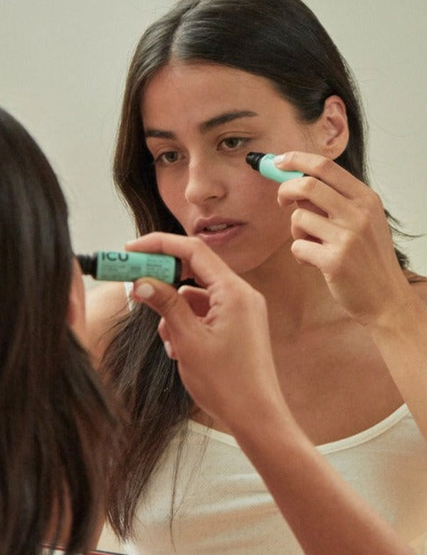 Woman applying eye serum in front of a mirror – Black Chicken Remedies ICU Intensive Care Eye Serum 9ml