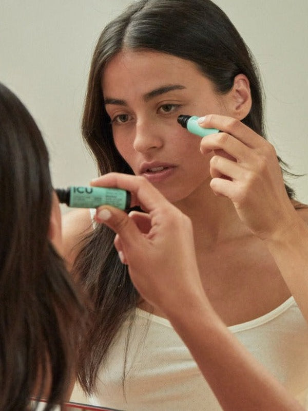 Woman applying eye serum in front of a mirror – Black Chicken Remedies ICU Intensive Care Eye Serum 9ml