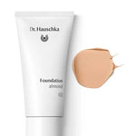 A white tube of Dr Hauschka Foundation 30ml is displayed beside a smear of beige, medium coverage natural foundation on a white background.