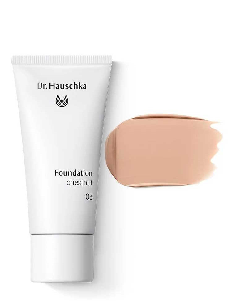 A white tube of Dr Hauschka Foundation 30ml is placed next to a beige natural foundation swatch, both offering medium coverage, on a white background.