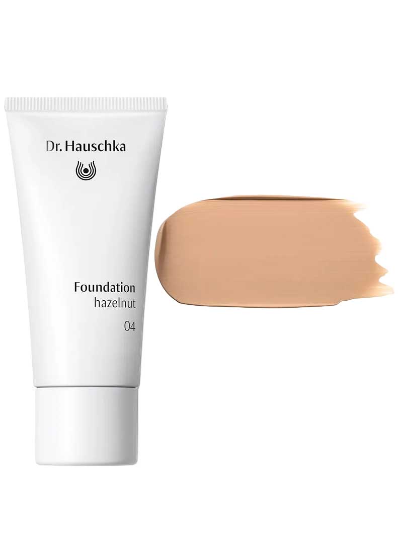 A white tube labeled Dr Hauschka Foundation 30ml stands beside a large swatch of medium coverage, natural foundation in medium beige on a white background.