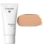 A white tube labeled Dr Hauschka Foundation 30ml stands beside a large swatch of medium coverage, natural foundation in medium beige on a white background.