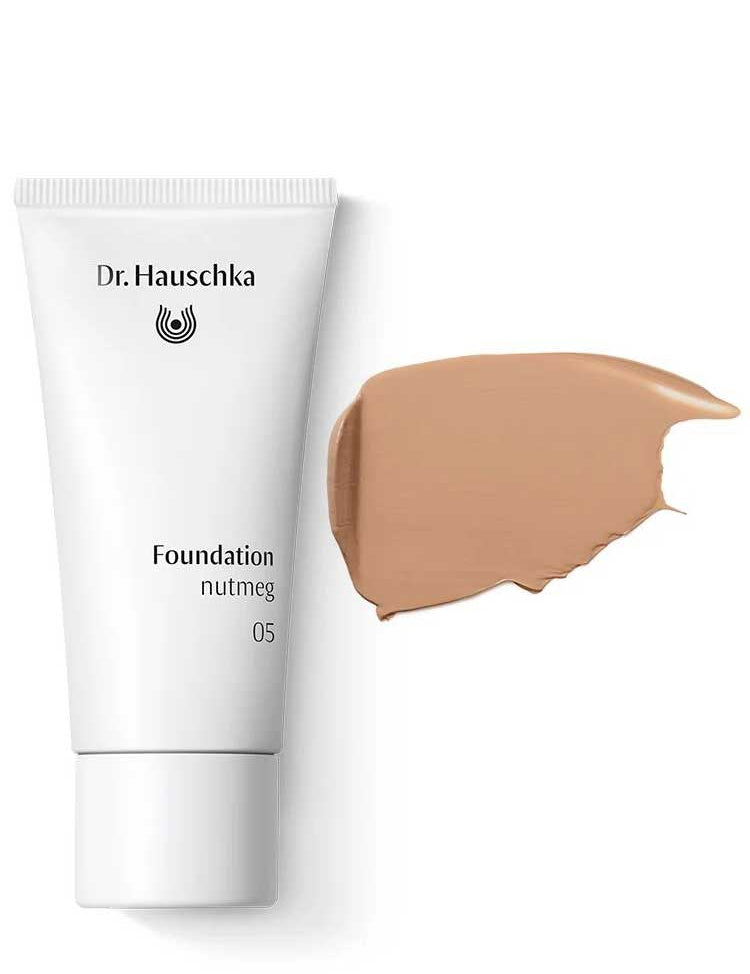 A white tube labeled Dr Hauschka Foundation 30ml is displayed next to a swatch of medium coverage natural foundation cream on a white background.