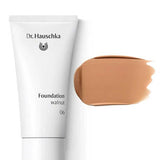 A white tube labeled Dr Hauschka Foundation 30ml sits next to a swatch of medium coverage natural foundation on a white background.