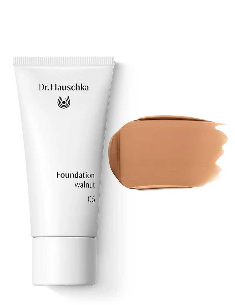 A white tube labeled Dr Hauschka Foundation 30ml sits next to a swatch of medium coverage natural foundation on a white background.