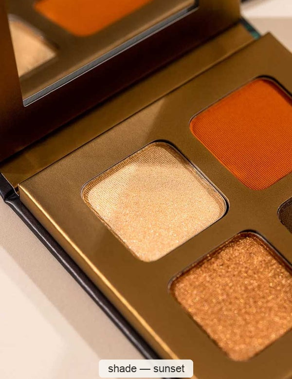 Close-up of an open gold INIKA Sunset eyeshadow quad, showing shimmering pale gold and copper pans beside matte orange and a partially cropped dark brown pan. The caption identifies the shade as Sunset.