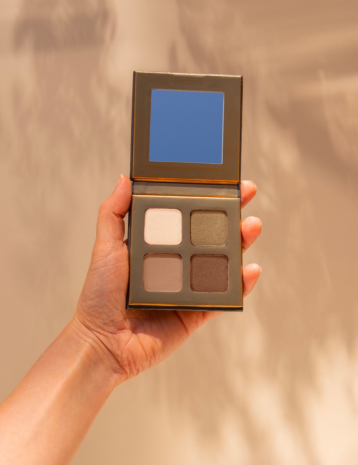 Woman’s hand holding INIKA Organic Eyeshadow Quad in Wind