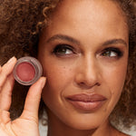 Model wearing and holding INIKA Organic Lip and Cheek Cream