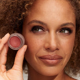 Model wearing and holding INIKA Organic Lip and Cheek Cream