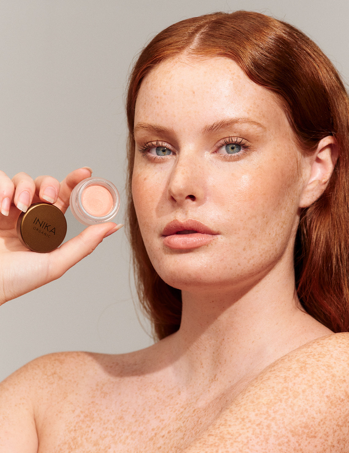 Model wearing and holding INIKA Organic Lip and Cheek Cream