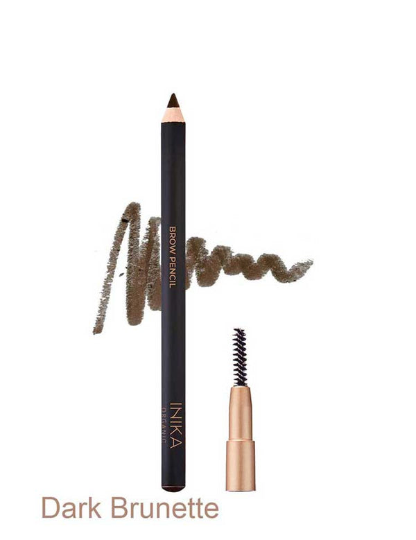 Black INIKA brow pencil in Dark Brunette standing beside a small spoolie brush in a gold cap, with a dark brown scribbled swatch behind the pencil and the shade name Dark Brunette printed below.