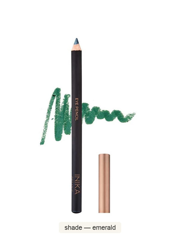 Black INIKA eyeliner pencil standing beside its bronze cap, with a green scribbled colour swatch behind it. The caption identifies the shade as Emerald.