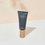 A 30ml tube of INIKA Organic Primer Matte Perfection, featuring a dark matte body and gold cap, stands upright on a white surface against a beige background.