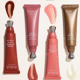 Four uncapped INIKA lip serum tubes arranged beside glossy swatches on a pale background, labelled Rosewood with red-brown serum, Peony with rose-pink serum, Blush with light pink serum and Clear with translucent serum.