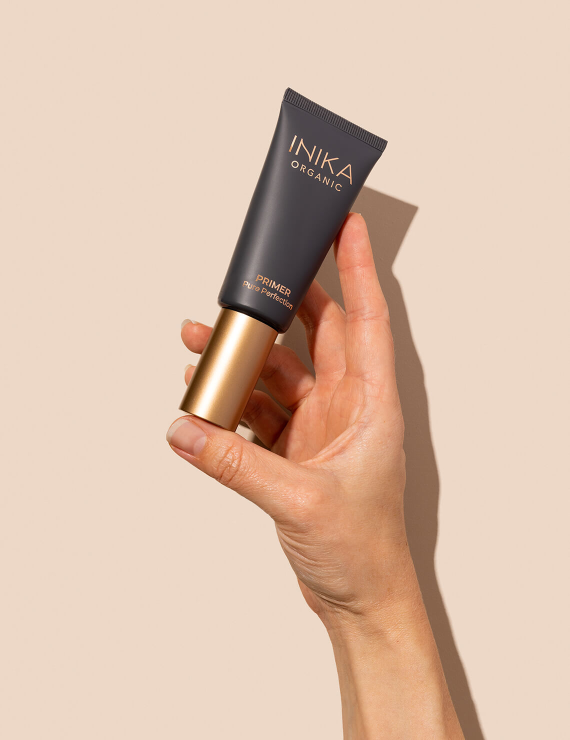 Hand holding INIKA Organic Pure Perfection Primer
