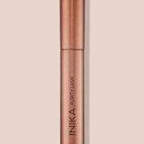 INIKA Organic Purity Lash Mascara in Black standing upright in a metallic rose-gold tube against a soft beige background.