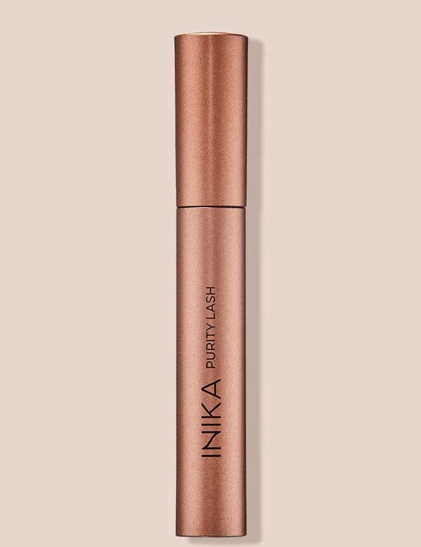 INIKA Organic Purity Lash Mascara in Black standing upright in a metallic rose-gold tube against a soft beige background.