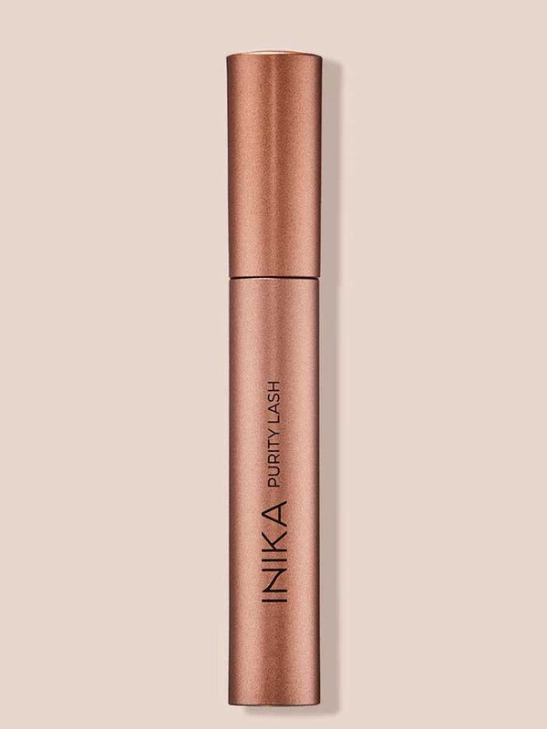 INIKA Organic Purity Lash Mascara in Black standing upright in a metallic rose-gold tube against a soft beige background.