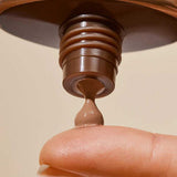 Close-up of INIKA Organic Tinted Natural Sunscreen SPF50+ being dispensed onto a fingertip from the open tube.