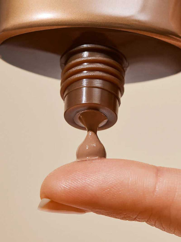 Close-up of INIKA Organic Tinted Natural Sunscreen SPF50+ being dispensed onto a fingertip from the open tube.