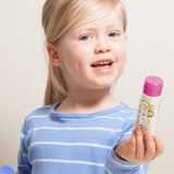 Smiling child holding Jack N' Jill Berries and Cream toothpaste and its purple cap against a bright white background.
