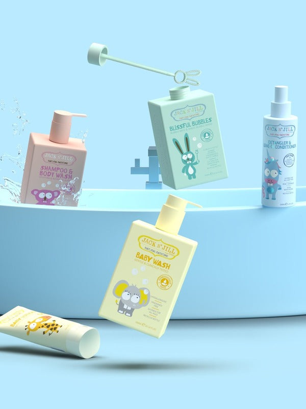 Colourful Jack N' Jill children's bath products arranged around a small blue bathtub, including baby wash, shampoo and body wash, bubble bath and spray.