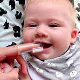 Smiling baby having their gums cleaned with the Jack N' Jill Stage 1 silicone finger brush while wearing a patterned bib.