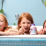 Children smiling over a blue-tiled bathtub while displaying colourful Jack N' Jill Tooth Sparkles bottles.