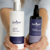 Person holding Juniper Calming Face and Body Wash and Calming Treatment Serum forward with both labels visible.