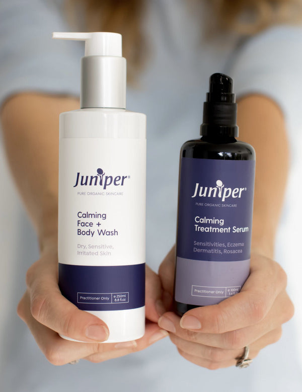 Person holding Juniper Calming Face and Body Wash and Calming Treatment Serum forward with both labels visible.