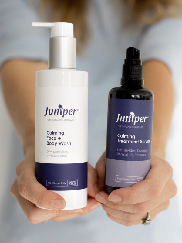 Person holding Juniper Calming Face and Body Wash and Calming Treatment Serum forward with both labels visible.