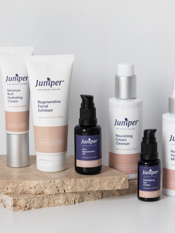 Juniper mature skincare range arranged on a natural stone platform, including the Revitalising Eye Cream with coordinating tubes and treatment bottles.