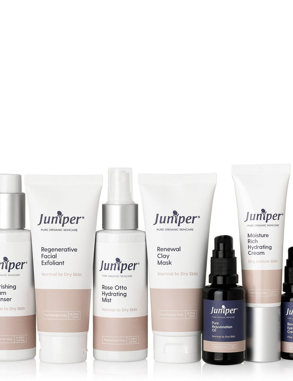 Seven Juniper skincare products arranged in a row on white: three white tubes, two tall white bottles and two small black pump bottles, with peach-coloured label bands.