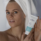 Young woman holding Juniper Teen Exfoliant beside her face.