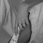 Black-and-white lifestyle image of a person holding a tube of Juniper Teen Lotion while seated.