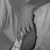 Black-and-white lifestyle image of a person holding a tube of Juniper Teen Lotion while seated.