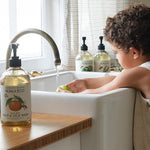Child helping at the kitchen sink with Koala Eco Dish Soap nearby