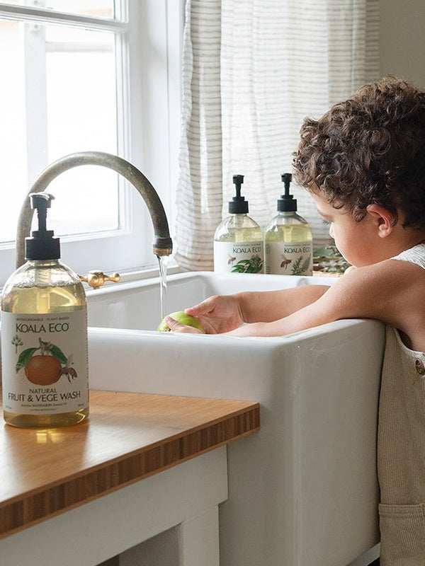 Child helping at the kitchen sink with Koala Eco Dish Soap nearby