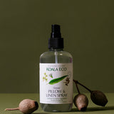 Koala Eco Pillow and Linen Spray styled with native gumnuts on a deep green background