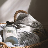 Koala Eco Pillow and Linen Spray resting in a woven laundry basket with soft blankets