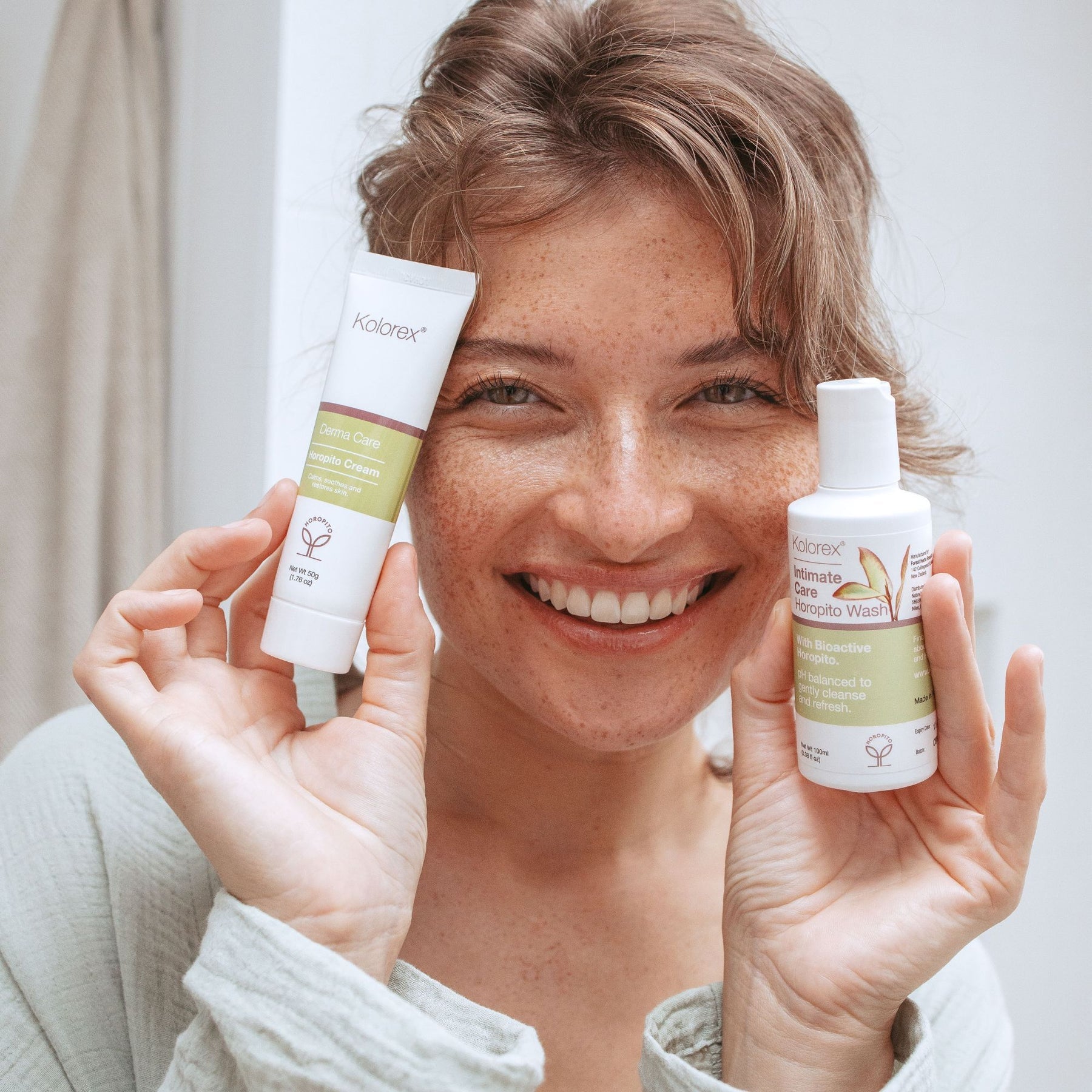 Woman holding Kolorex Horopito Skin Cream and wash beside her face