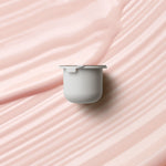 KORA Organics Kakadu Plum Vitamin C Eye Cream refill pod on a soft pink cream-texture background